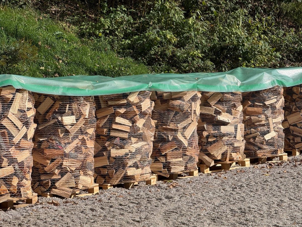 Brennholz-Gebinde zu 1,5 srm auf Paletten, abgedeckt im Freiluftlager von AL-Holz